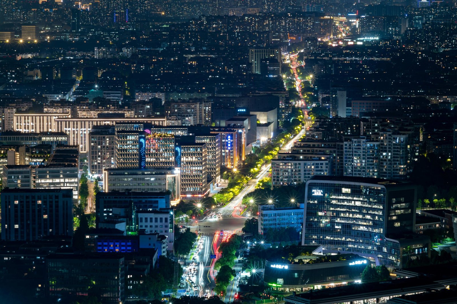 Aerial view of a city's vibrant night scene with illuminated buildings and streets.