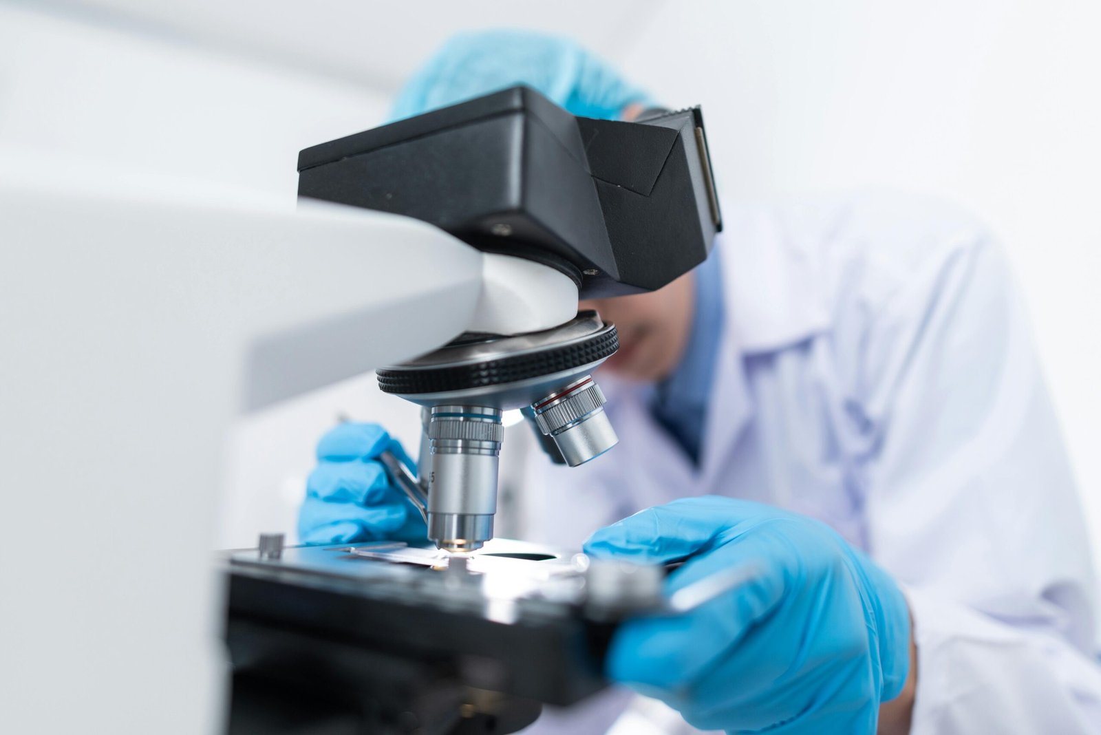 Close-up of a scientist examining samples under a microscope in a lab setting.